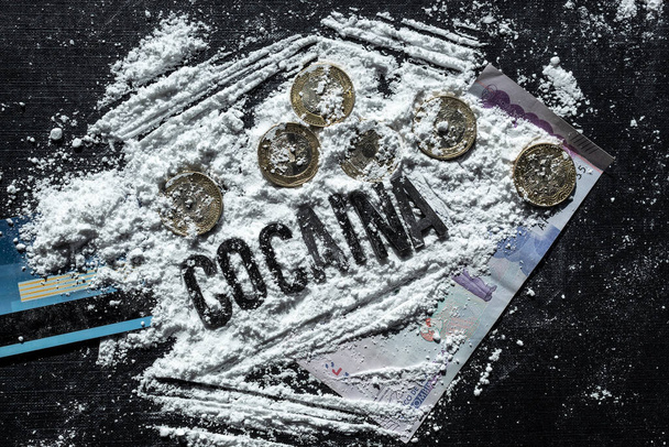 Близко к кокаиновому испанскому буквенному слову над линиями кокаина, колумбийскими монетами, колумбийской денежной бумагой и синей кредиткой на чёрном фоне. Концепция наркотиков и наркомании
 - Фото, изображение