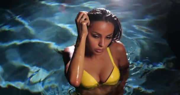 Donna sexy in piscina di notte indossando bikini giallo - Filmati, video