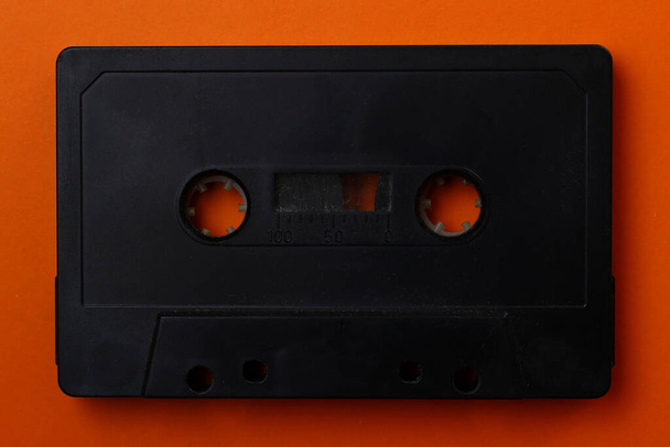 Schwarze Audiokassette in Nahaufnahme auf orangefarbenem Hintergrund - Foto, Bild