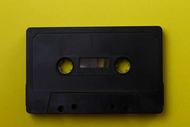 Черная аудиокассета крупным планом на жёлтом фоне
 - Фото, изображение