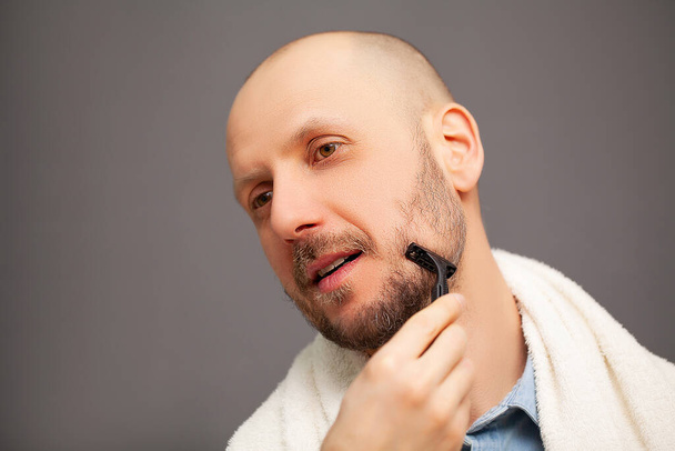 Banyodaki adam tıraş bıçağıyla sakalını kesiyor. - Fotoğraf, Görsel