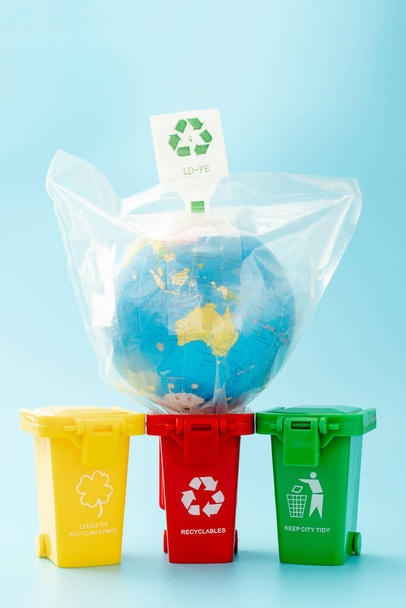 Sárga, zöld és piros újrahasznosító dobozok újrahasznosítási szimbólummal, kék háttérrel. Tartsd rendben a várost, hagyd itt az újrahasznosító szimbólumot. Természetvédelmi koncepció. - Fotó, kép