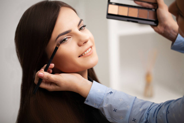 Makeup καλλιτέχνης κάνει επαγγελματική μακιγιάζ στον πελάτη στο σπίτι της - Φωτογραφία, εικόνα