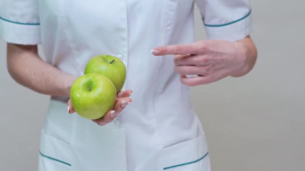 nutritionist doctor healthy lifestyle concept - holding two organic green apples - Imágenes, Vídeo