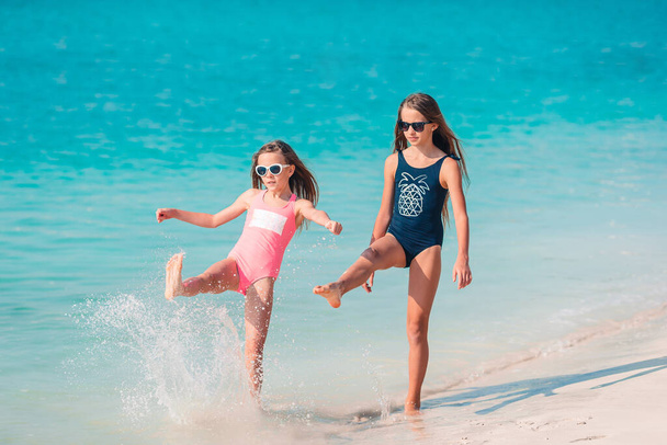 Маленькие веселые девочки веселятся на тропическом пляже, играя вместе.. - Фото, изображение