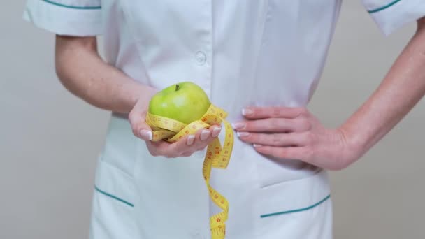 nutritionist doctor healthy lifestyle concept - holding organic green apple and measuring tape - Materiał filmowy, wideo