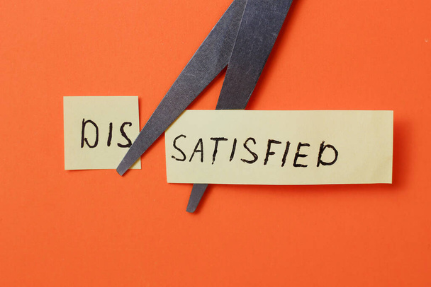 The inscription on the sticker: "DISSATISFIED" cut in half on an orange background - Photo, Image