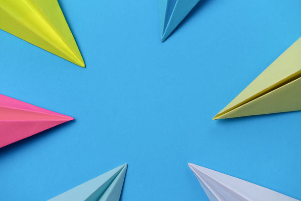 Veelkleurige neuzen van papieren vliegtuigen op een blauwe achtergrond met plaats voor tekst. - Foto, afbeelding