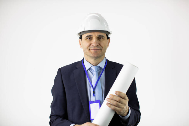 pozytywny inżynier konstruktor w kasku formalna odzież trzyma zwinięty rysunek - Zdjęcie, obraz