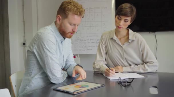 Successful business man and smiling businesswoman discussing while using digital tablet in office. Happy business team working in new company. Mature businessman showing data on screen to beautiful business woman. - Záběry, video