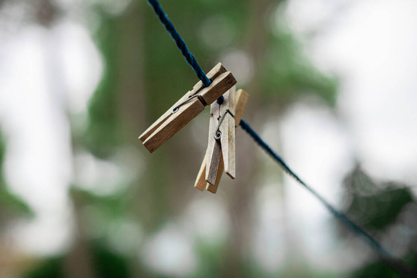 Wooden clothespins fastened on a blue rope with the background out of focus - Photo, Image