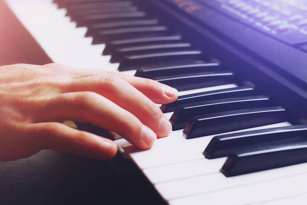 Muzikanten hand op de toetsen van een synthesizer, achtergrond, afgezwakt - Foto, afbeelding