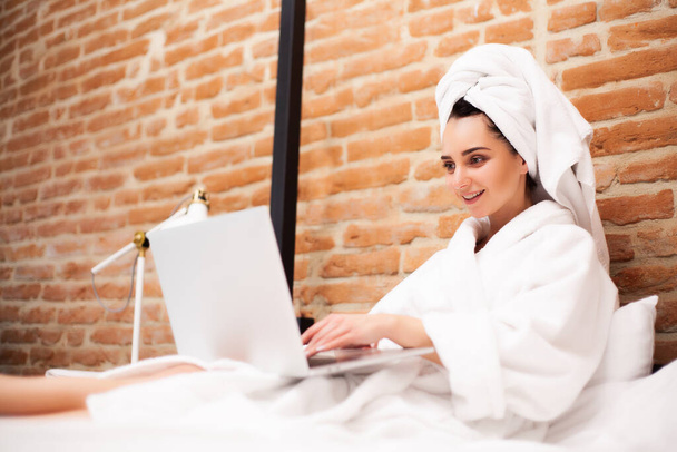 Pretty woman after shower chatting on a laptop - Zdjęcie, obraz