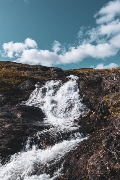 Soleado blanco escénico noruego potente cascada del río cascada con rocas oscuras y cielo azul brillante. Naturaleza viaje limpio caída agua vertical paisaje
 - Foto, imagen