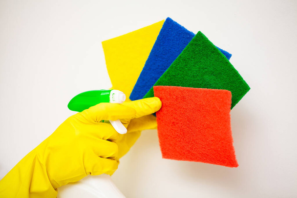 Primer plano de la mano en manoplas amarillas que sostienen los suministros de limpieza
. - Foto, Imagen