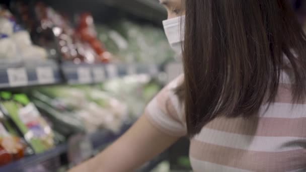 Yavaş Hareketli Asyalı kadınlar tıbbi maske takıyor sebze raflarına, gıda marketlerine, kovid19 Corona virüsü salgını sırasında yaşam tarzlarına, ev yemeği hazırlıklarına, yiyecek stoklarına bakıyorlar. - Video, Çekim