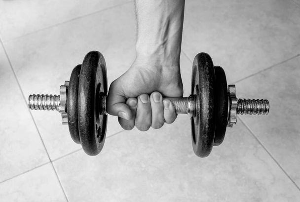 Closeup to male hand squeezing an old iron dumbell. Ideal for fitness, sports, healthy life, gym and home workout. - 写真・画像