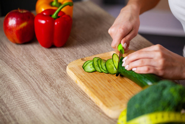 Primo piano di donna fette cetriolo per insalata fresca
 - Foto, immagini