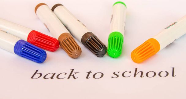 Ένα σύνολο πολύχρωμων δεικτών σε λευκό φόντο και η επιγραφή-πίσω στο σχολείο, η έννοια της εκπαίδευσης. - Φωτογραφία, εικόνα