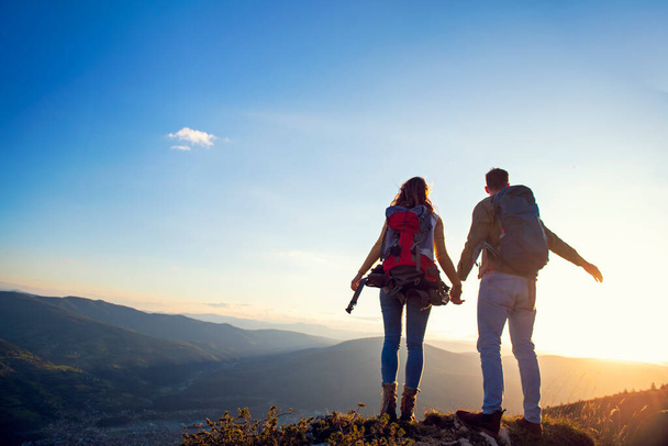 happy couple man and woman tourist at top of mountain at sunset outdoors during a hike in summer - Foto, Imagen