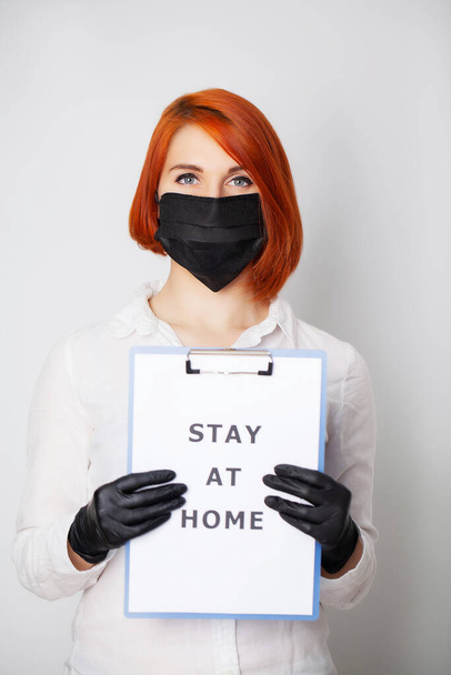 Frau hält Blanko mit Aufschrift "Bleiben Sie zu Hause" und ruft dazu auf, die Verbreitung von Covid-19 zu stoppen - Foto, Bild