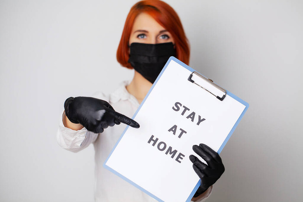 Mulher segurando em branco com inscrição ficar em casa chamando para parar de espalhar covid-19
 - Foto, Imagem