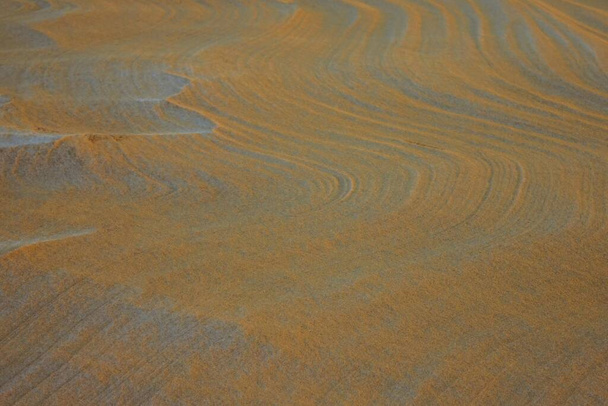 抽象化、砂の背景に波線。黄色、ベージュのトーン。側面照明. - 写真・画像