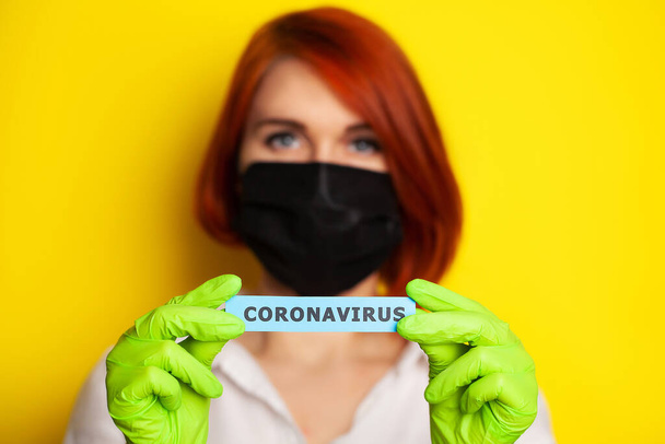Vrouw met beschermende handschoenen met inscriptie coronavirus. - Foto, afbeelding