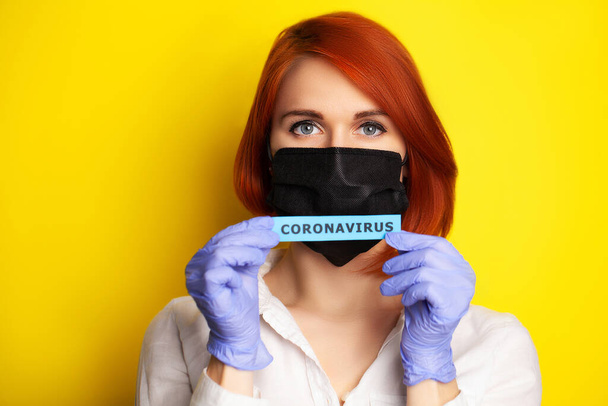 Femme en gants de protection tenant une inscription coronavirus
. - Photo, image