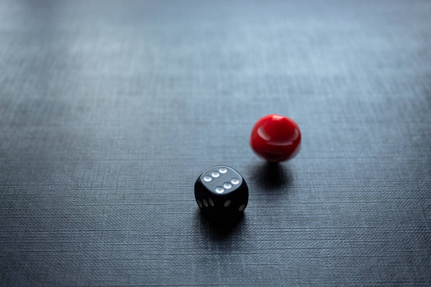 Closeup to a dices, one dice is red and one black dice is spinning over a black background. Ideal for gamble, board games and bets - Photo, Image