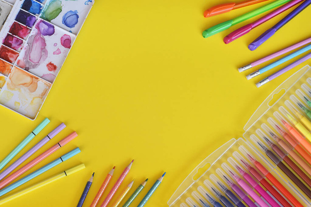 Marcadores, colores, plumones, lápices y acuarelas sobre fondo amarillo. - Foto, imagen