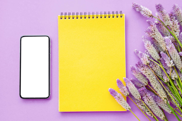 carta gialla vuota vista dall'alto con fiore viola e smart phone composizione laica piatta su sfondo viola, modello per testo
 - Foto, immagini