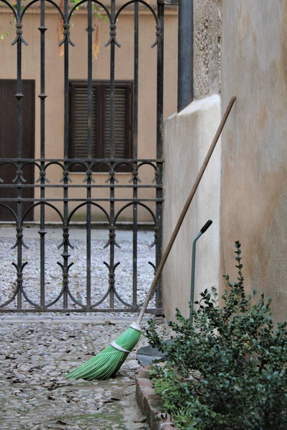 детали кованых железных ворот с метлой, прислоненной к стене на улице в Палермо, Италия
 - Фото, изображение