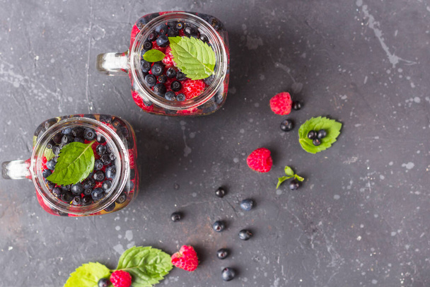 Fresh cool detox drink with raspberries, blueberries and kiwi in mason jar mug. Lemonade in a glass with a mint. The concept of proper nutrition and healthy eating. Fitness diet. Flat lay - Foto, imagen