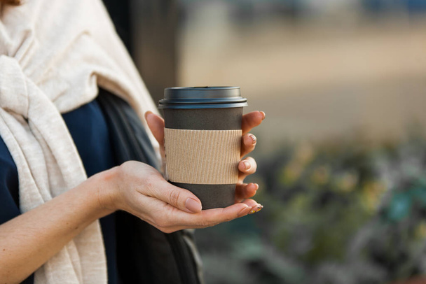 beautiful womans hands with cup of coffeen in craft paper in the street - Φωτογραφία, εικόνα