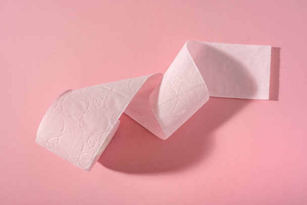 Eine Rolle rosa Toilettenpapier auf rosa Hintergrund. Hygieneartikel. - Foto, Bild