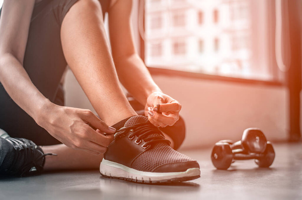  woman tying shoelaces at gym. - Zdjęcie, obraz