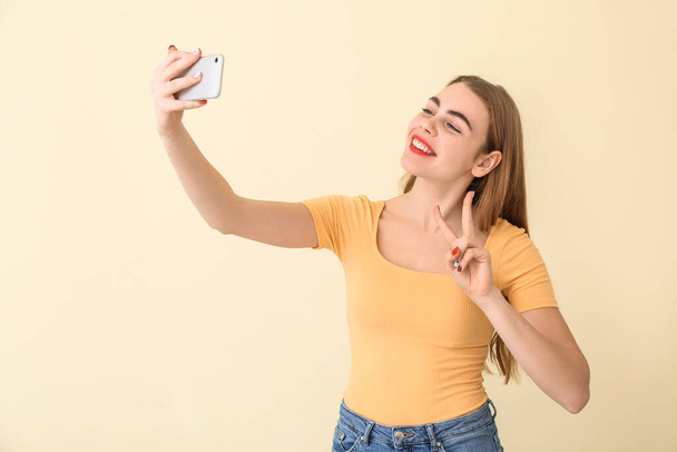 Beautiful young woman taking selfie on color background - Foto, immagini