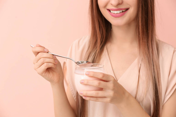 Young woman with tasty yogurt on color background, closeup - Photo, Image
