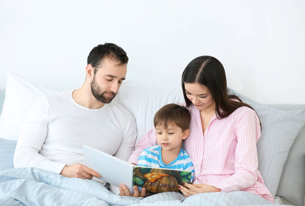 Happy family reading book in bedroom at home - Φωτογραφία, εικόνα