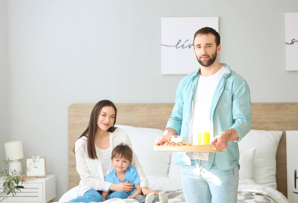Glücklicher Mann bringt sein Familienfrühstück ins Bett - Foto, Bild