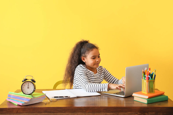 Kleines afroamerikanisches Mädchen macht Hausaufgaben vor farbigem Hintergrund - Foto, Bild