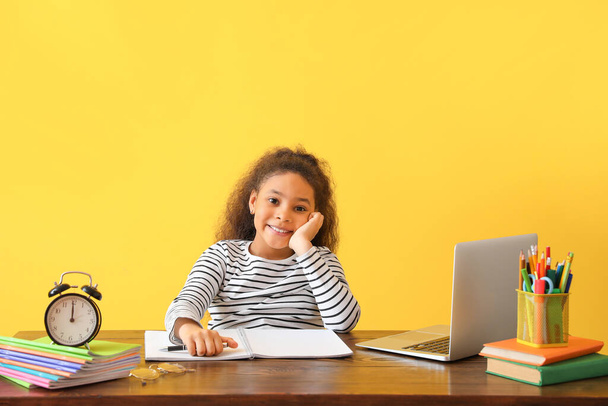 Маленькая афроамериканка делает домашнее задание на цветном фоне
 - Фото, изображение