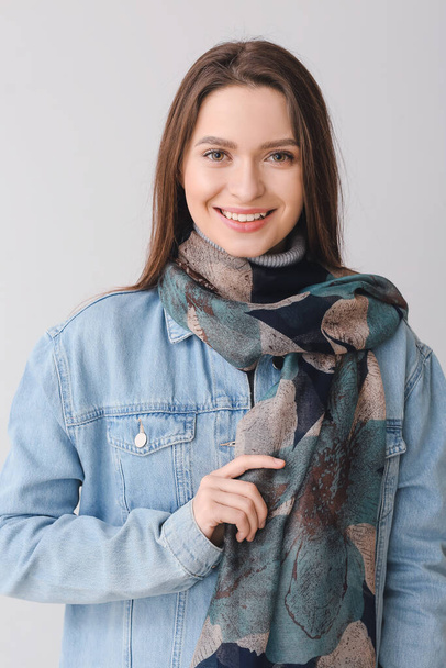 Beautiful young woman with stylish scarf on grey background - Foto, Bild
