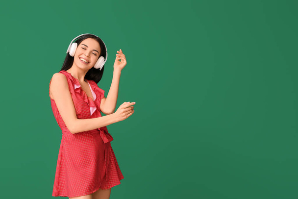 Belle jeune femme écoutant de la musique et dansant sur fond de couleur - Photo, image