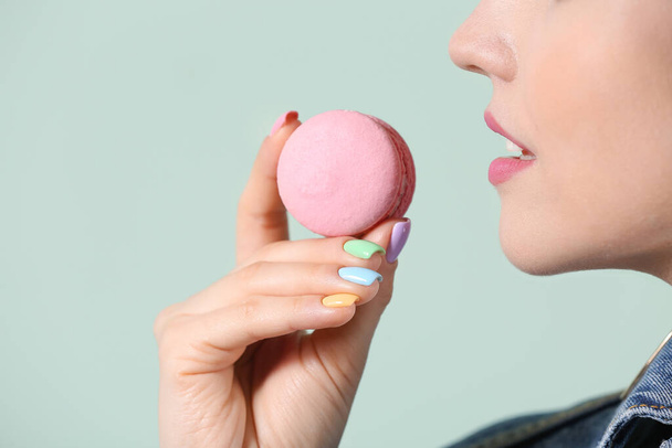 Young woman with beautiful manicure and macaron on color background, closeup - 写真・画像