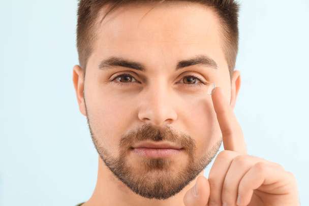 Young man with contact lens on color background - Φωτογραφία, εικόνα