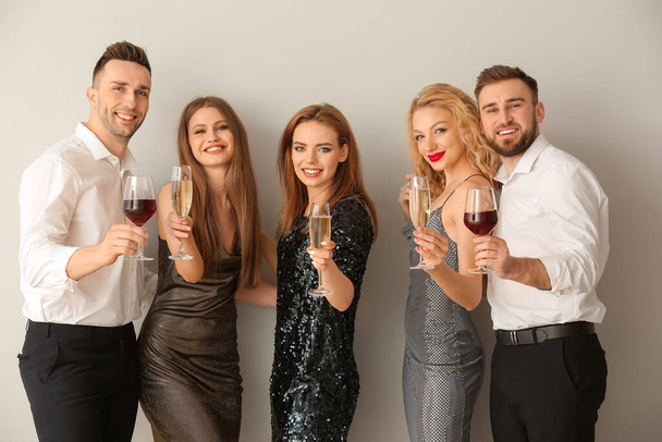 Šťastní lidé s brýlemi alkoholických nápojů na šedém pozadí - Fotografie, Obrázek