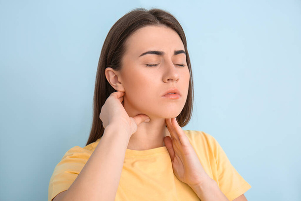 Young woman checking thyroid gland on color background - Photo, Image