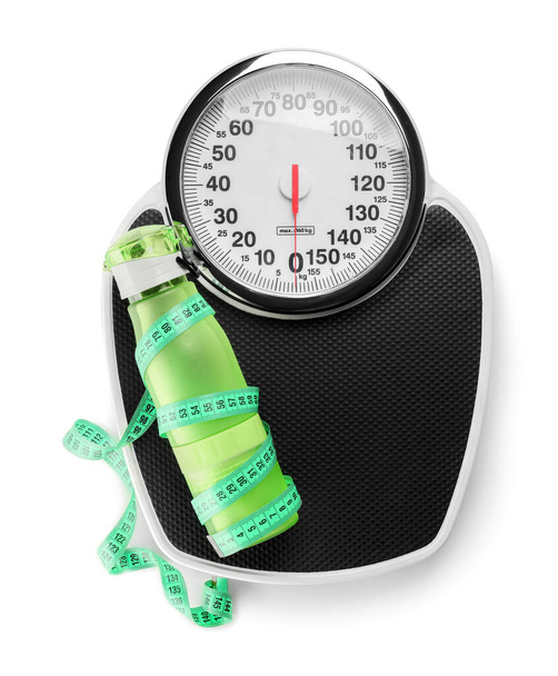 Weight scales with measuring tape and bottle of water on white background. Slimming concept - Photo, Image